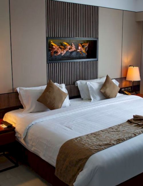A modern hotel room featuring a king-sized bed, two bedside tables with lamps, a decorative wall, and a window with curtains.