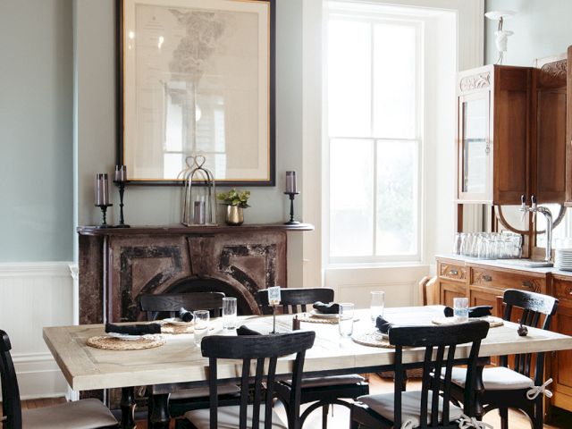 A dining room with a table set for dinner, a fireplace, and a window.