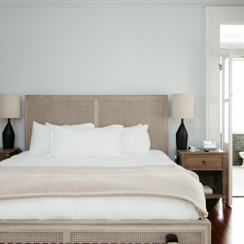 A cozy bedroom with a neutral palette: a large bed, plush pillows, matching nightstands, and soft natural light streaming in.