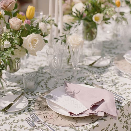 A fancy table set for a banquet with floral centerpiece, glassware, and folded napkins, creating an elegant, intimate dining ambiance.