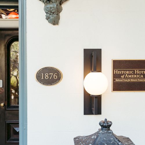 The image shows a building entrance with a plaque reading "Historic Hotels of America" and an oval sign with "1876" on it.