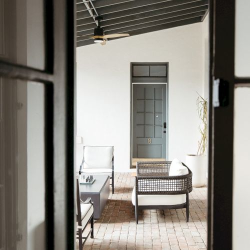 The image shows an outdoor patio with seating furniture and a brick floor, viewed through a glass door.