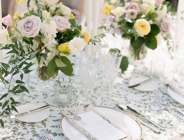 A beautifully set dining table with flowers, plates, glasses, and silverware