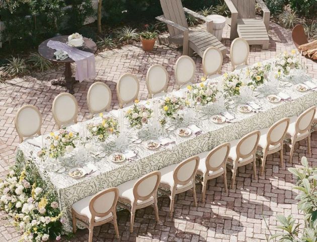 A beautifully set outdoor dining table with flowers and plates