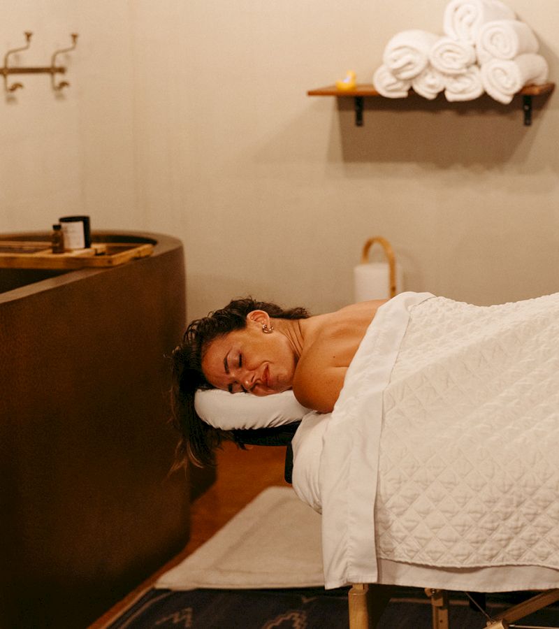 a woman lying on a massage table in a spa with a tub