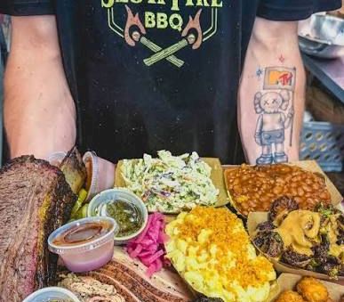 A platter of barbecue food including meat, sides, and sauces.