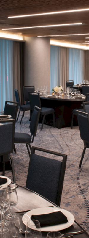 The image shows an elegant banquet hall set up for a formal event with round tables, chairs, table settings, and decorative centerpieces.